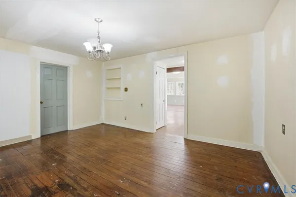 an empty room with wooden floor chandelier and closet