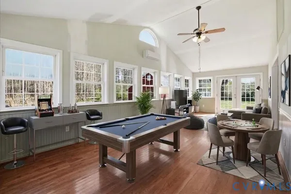 a room with furniture pool table wooden floor and windows