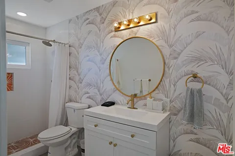 a bathroom with a toilet sink vanity granite and a mirror