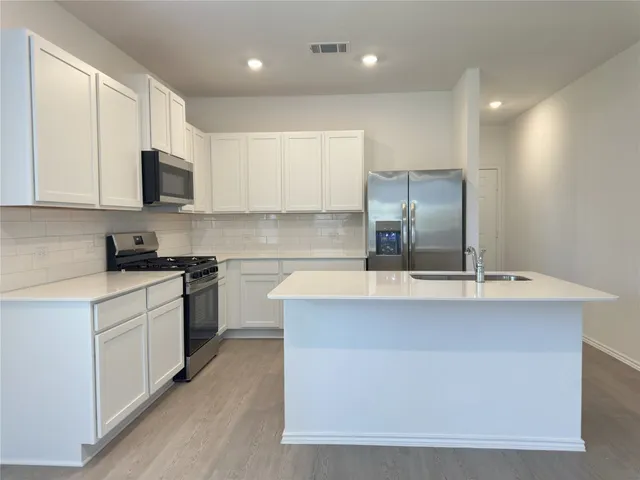 a kitchen with kitchen island a sink stainless steel appliances and cabinets