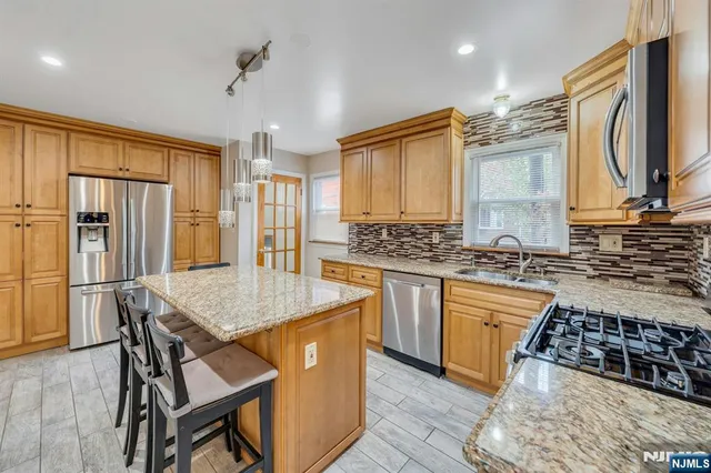 a kitchen with stainless steel appliances granite countertop a stove refrigerator sink and cabinets