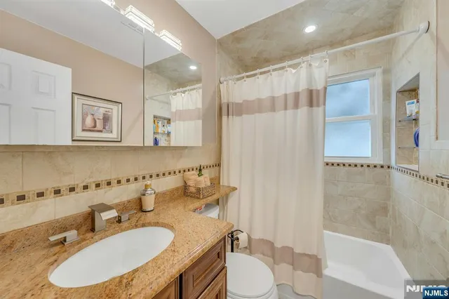 a bathroom with a granite countertop sink toilet a mirror a bathtub and shower