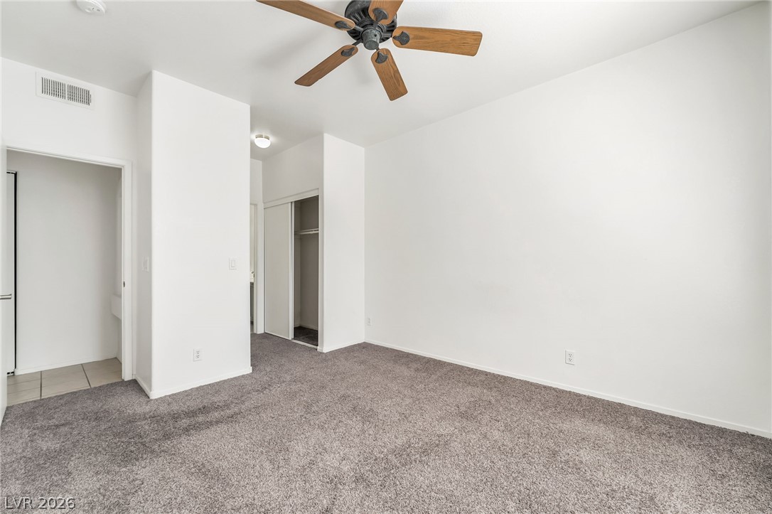 2201 Ramsgate Drive, Unit 811 Henderson, NV 89074 - Photo 18 of 36 A comfortable bedroom features plush carpeting and a ceiling fan, offering a tranquil retreat.