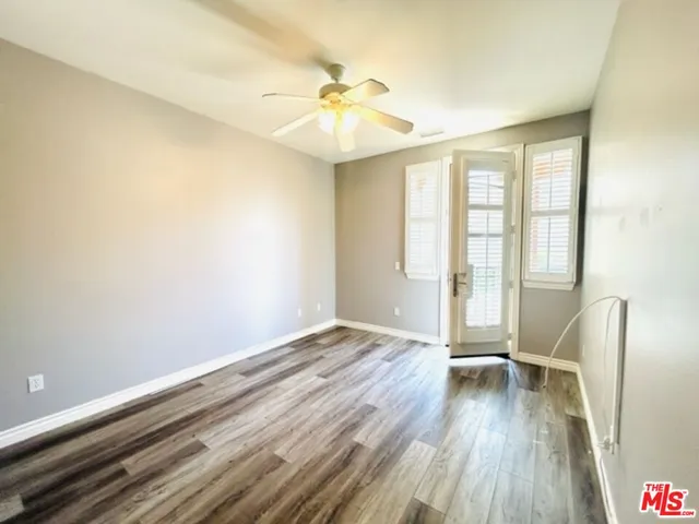 an empty room with wooden floor fan and windows