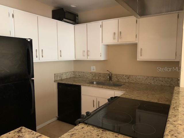 120 America Street, Unit 7 Orlando, FL 32801 - Photo 3 of 13 a kitchen with granite countertop white cabinets and refrigerator