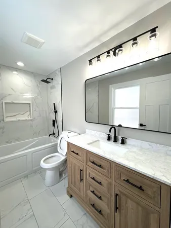 a bathroom with a granite countertop sink mirror vanity bathtub and a toilet