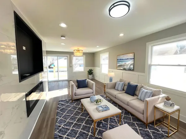 a living room with furniture a flat screen tv and a window