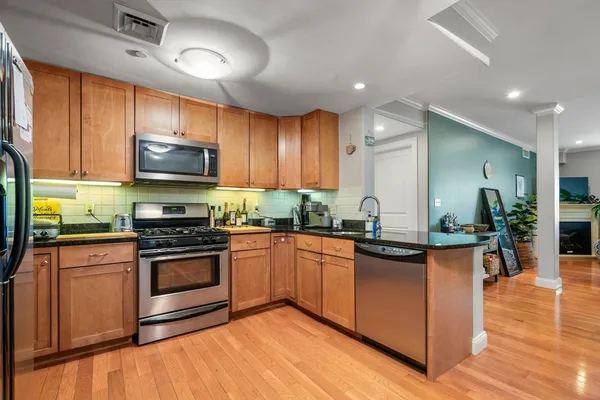 a kitchen with stainless steel appliances granite countertop a stove a sink dishwasher and a microwave oven with wooden floor