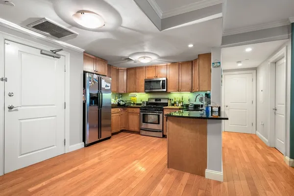 a kitchen with stainless steel appliances kitchen island granite countertop wooden floors refrigerator and cabinets