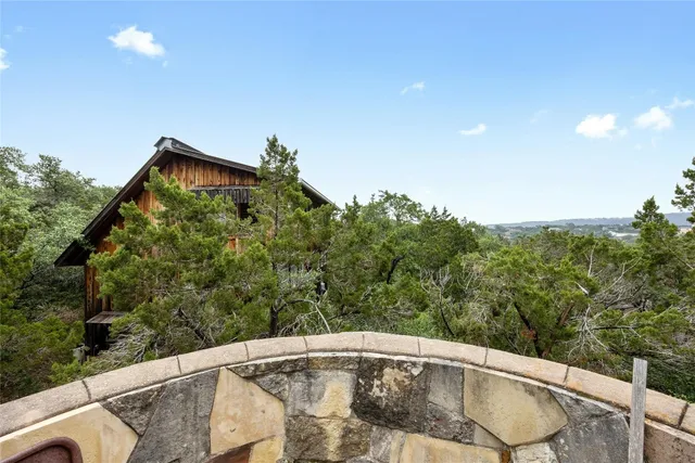 a backyard of a house with large trees and wooden fence