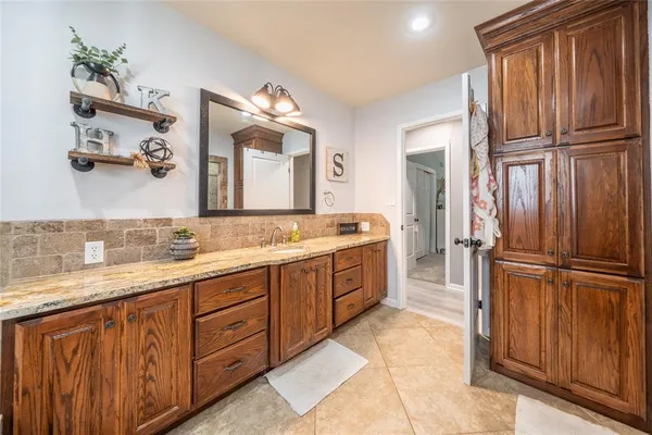 a spacious bathroom with a granite countertop sink a mirror and cabinets
