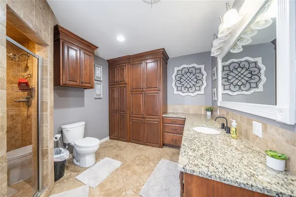 a bathroom with a granite countertop toilet sink and mirror