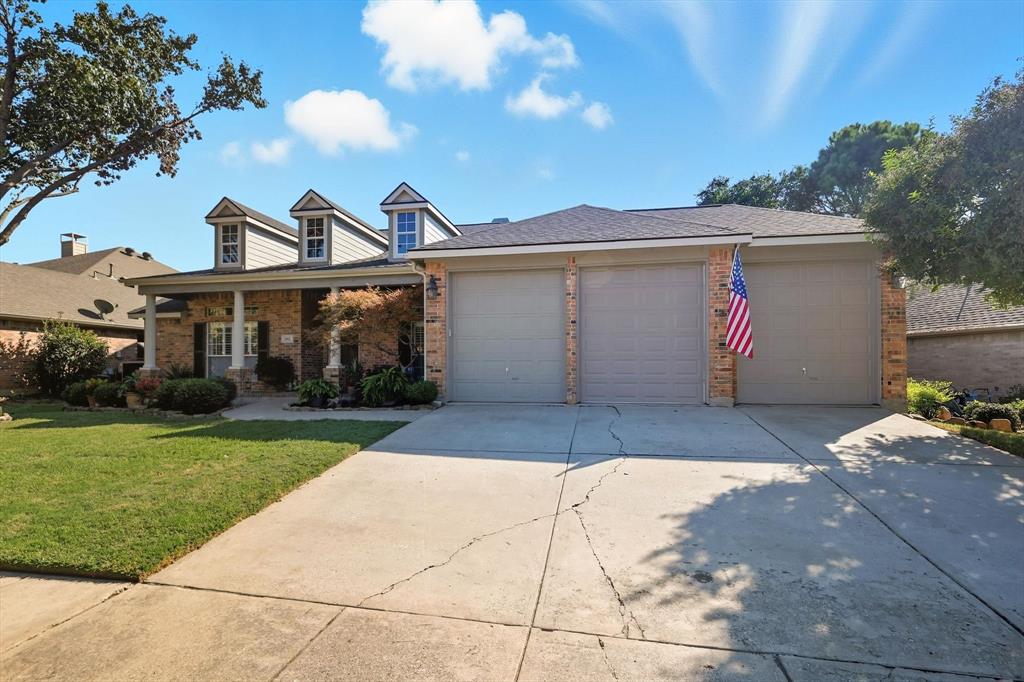 View of front of house with brick siding, a porch, driveway, and a front lawn