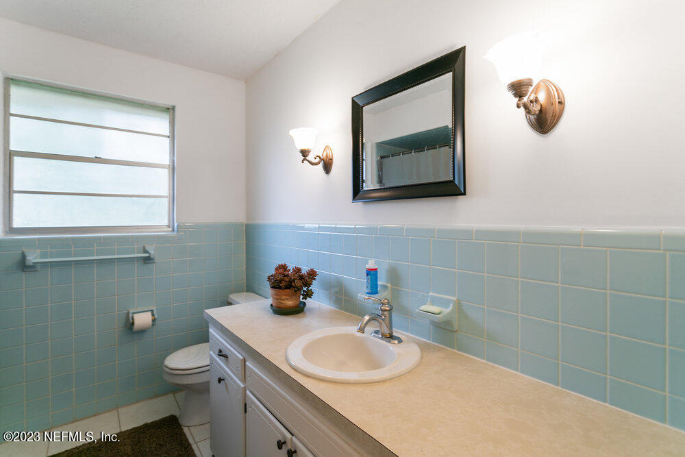 1807 Mill Creek Road Jacksonville, FL 32277 - Photo 11 of 18 a bathroom with a toilet sink vanity and mirror