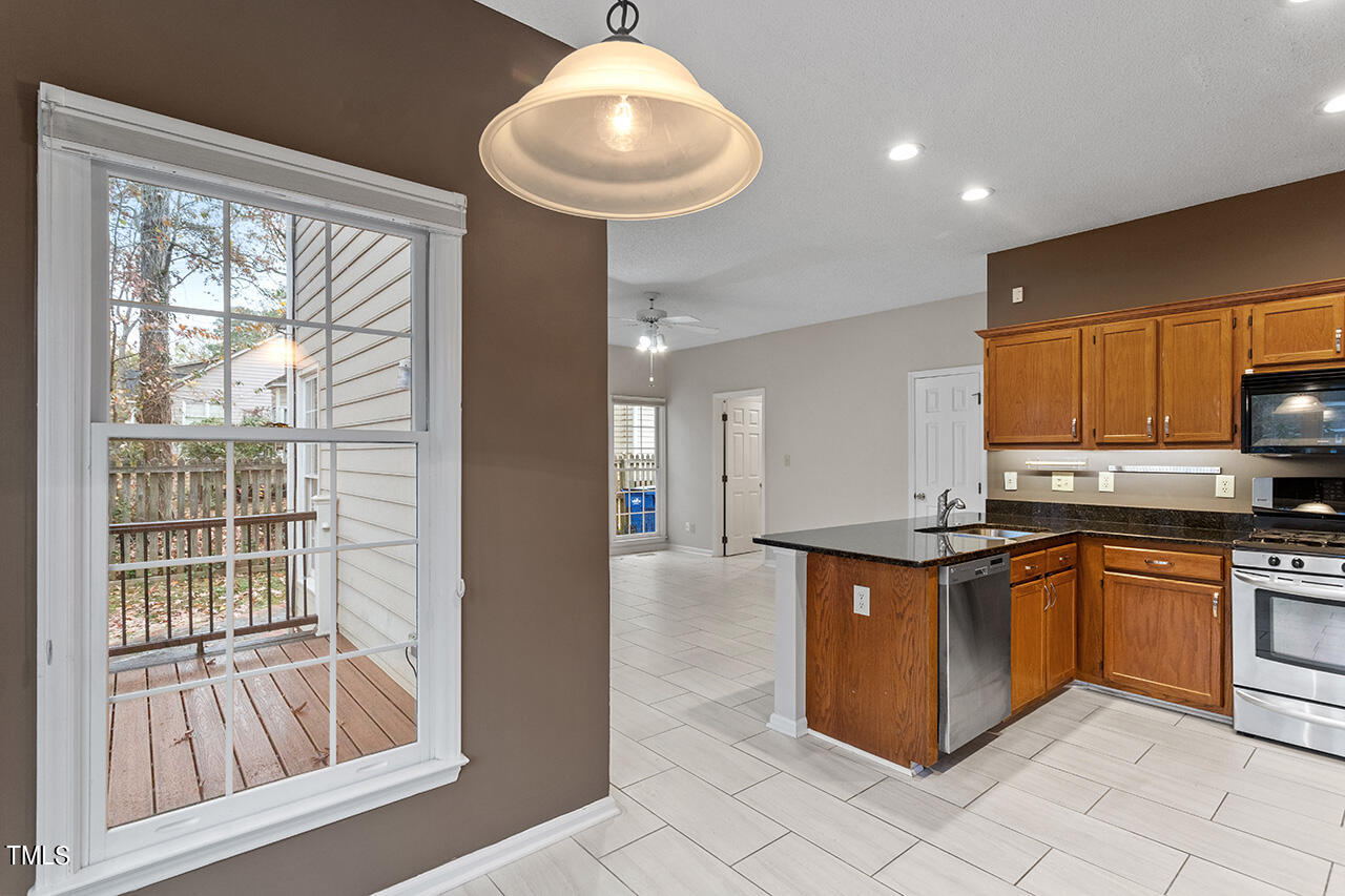 11932 North Exeter Way Raleigh, NC 27613 - Photo 21 of 35 a kitchen with stainless steel appliances granite countertop a stove a sink and a microwave