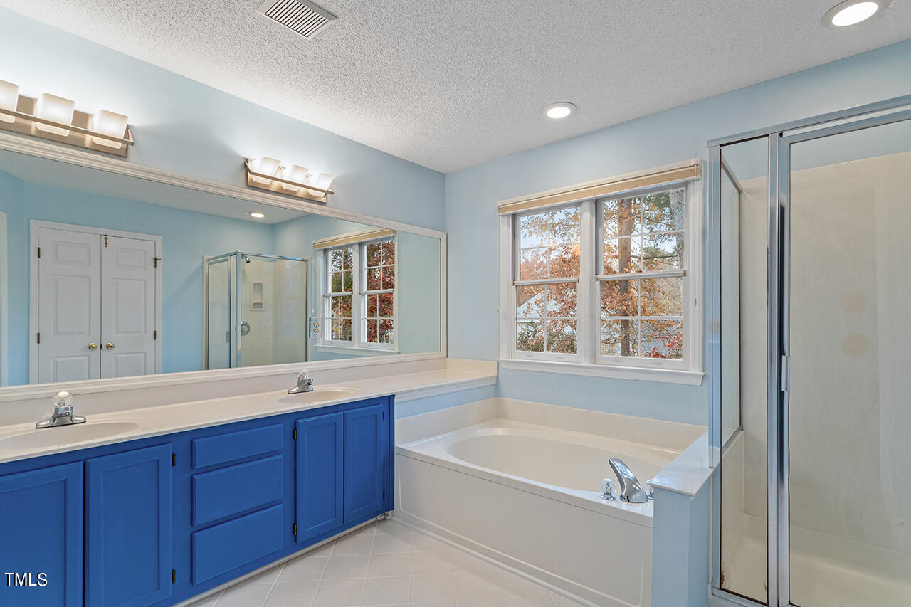 11932 North Exeter Way Raleigh, NC 27613 - Photo 31 of 35 a spacious bathroom with a tub sink shower and mirror