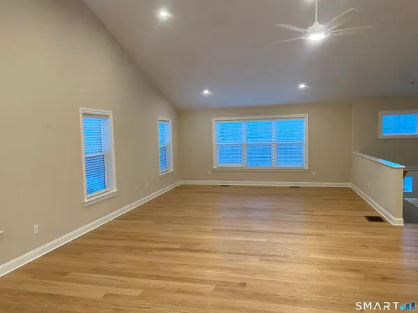 a view of an empty room with window and wooden floor