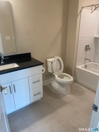 a bathroom with a granite countertop toilet sink and mirror