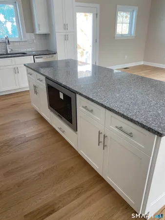 a kitchen with granite countertop white cabinets and a wooden floor