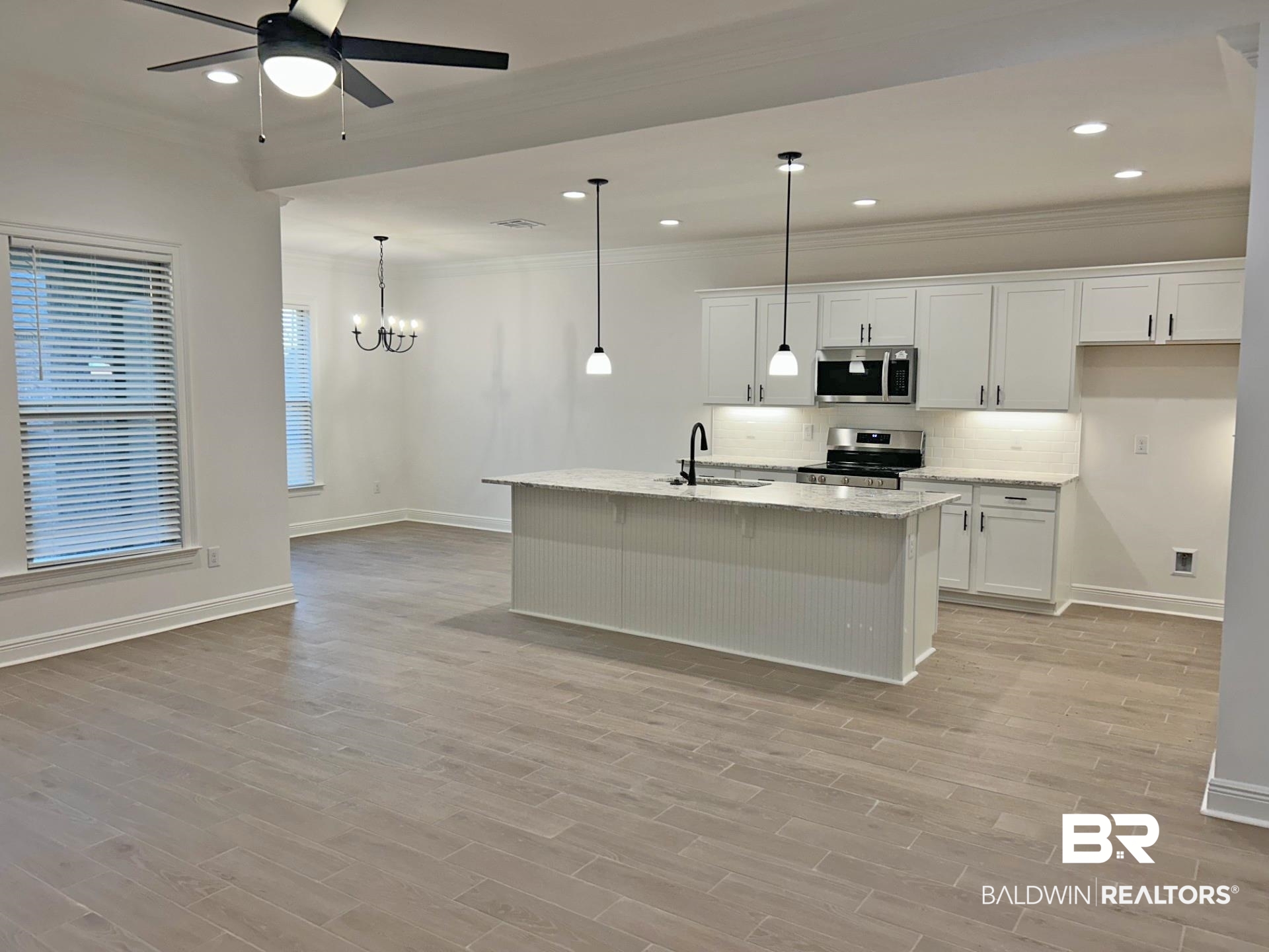 1744 Breckinridge Place Foley, AL 36535 - Photo 8 of 26 Kitchen featuring white cabinetry, light stone counters, a center island with sink, stainless steel appliances, and suspended lighting