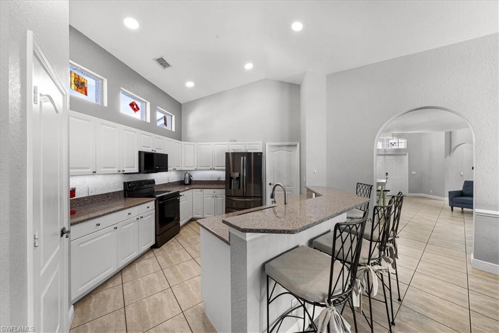 297 Sawgrass Court Naples, FL 34110 - Photo 12 of 31 a kitchen with stainless steel appliances granite countertop a stove top oven a sink a dining table and chairs with wooden floor