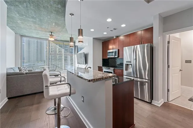 a kitchen with stainless steel appliances kitchen island granite countertop a refrigerator and a stove top oven