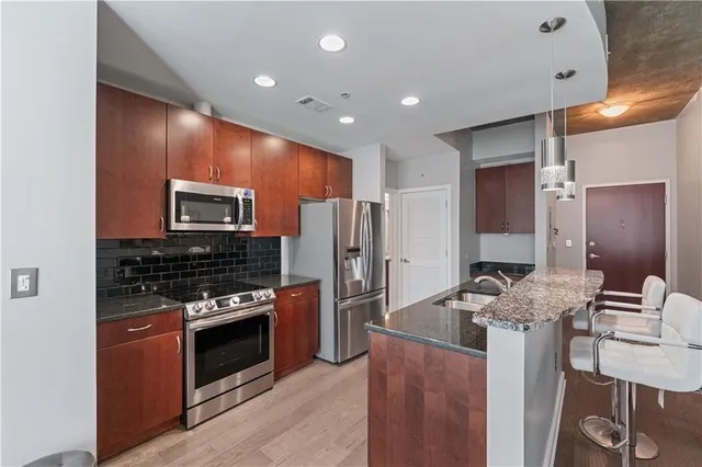 a kitchen with stainless steel appliances granite countertop a stove refrigerator sink and microwave