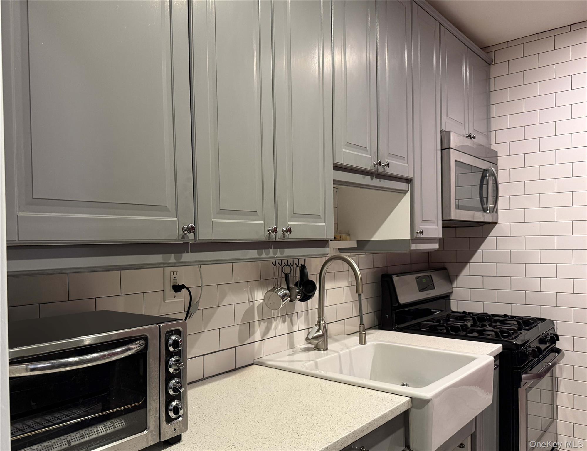 76-10 34th Avenue, Unit 3T Queens, NY 11372 - Photo 3 of 16 a kitchen with granite countertop a sink stainless steel appliances and cabinets