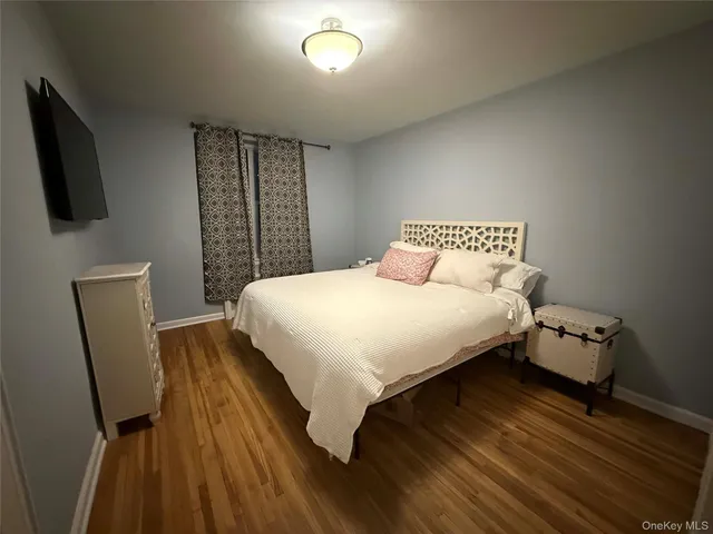 a bedroom with a bed a flat screen tv and dresser