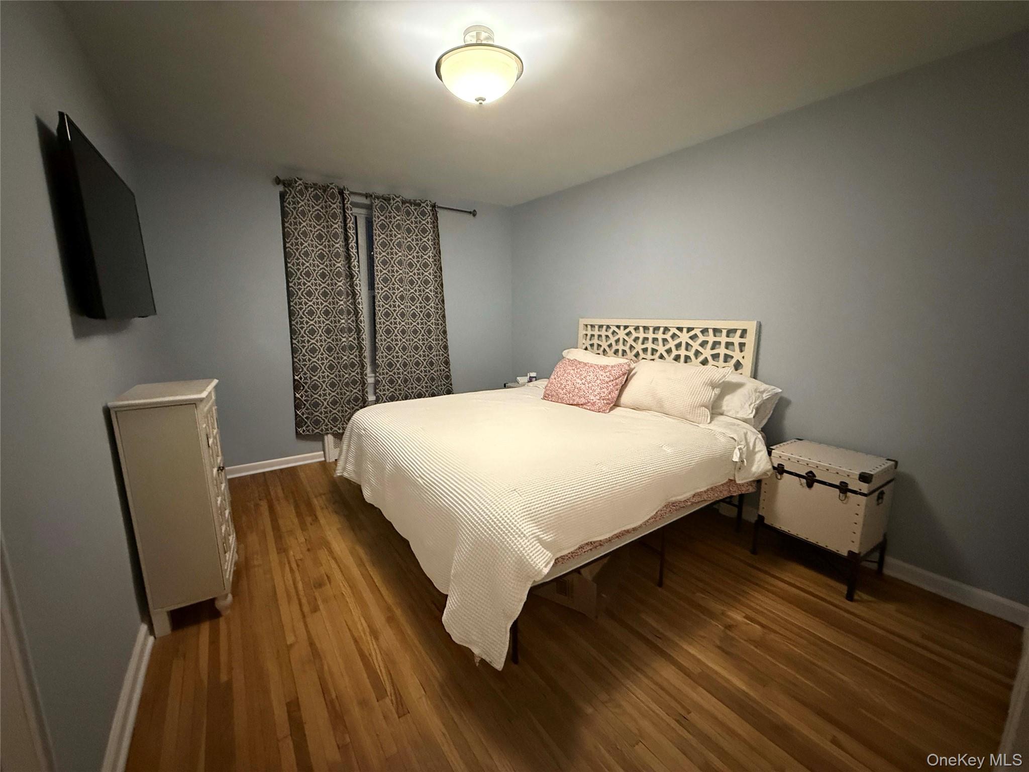76-10 34th Avenue, Unit 3T Queens, NY 11372 - Photo 10 of 16 a bedroom with a bed a flat screen tv and dresser