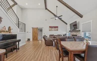 a kitchen with stainless steel appliances a refrigerator a stove a dining table and chairs with wooden floor