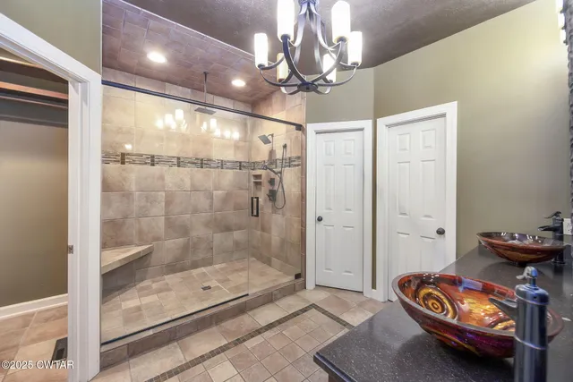 a bathroom with a sink a light fixture and a glass door shower