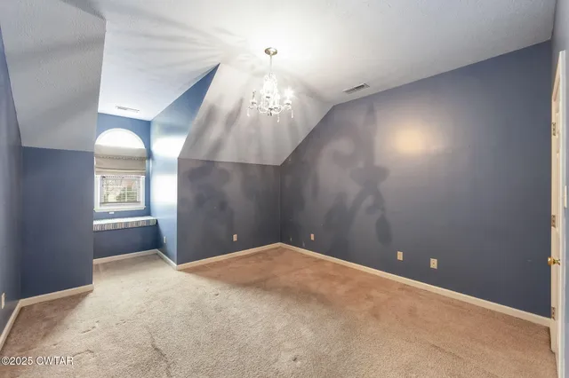 a view of an empty room with a chandelier fan