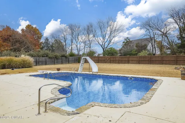 a view of a swimming pool with a lake and trees in the background