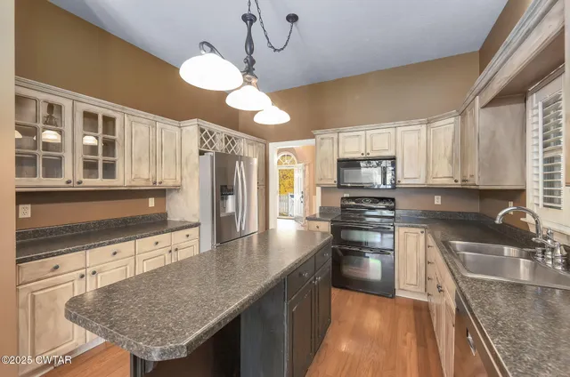 a kitchen with stainless steel appliances granite countertop a sink refrigerator and cabinets