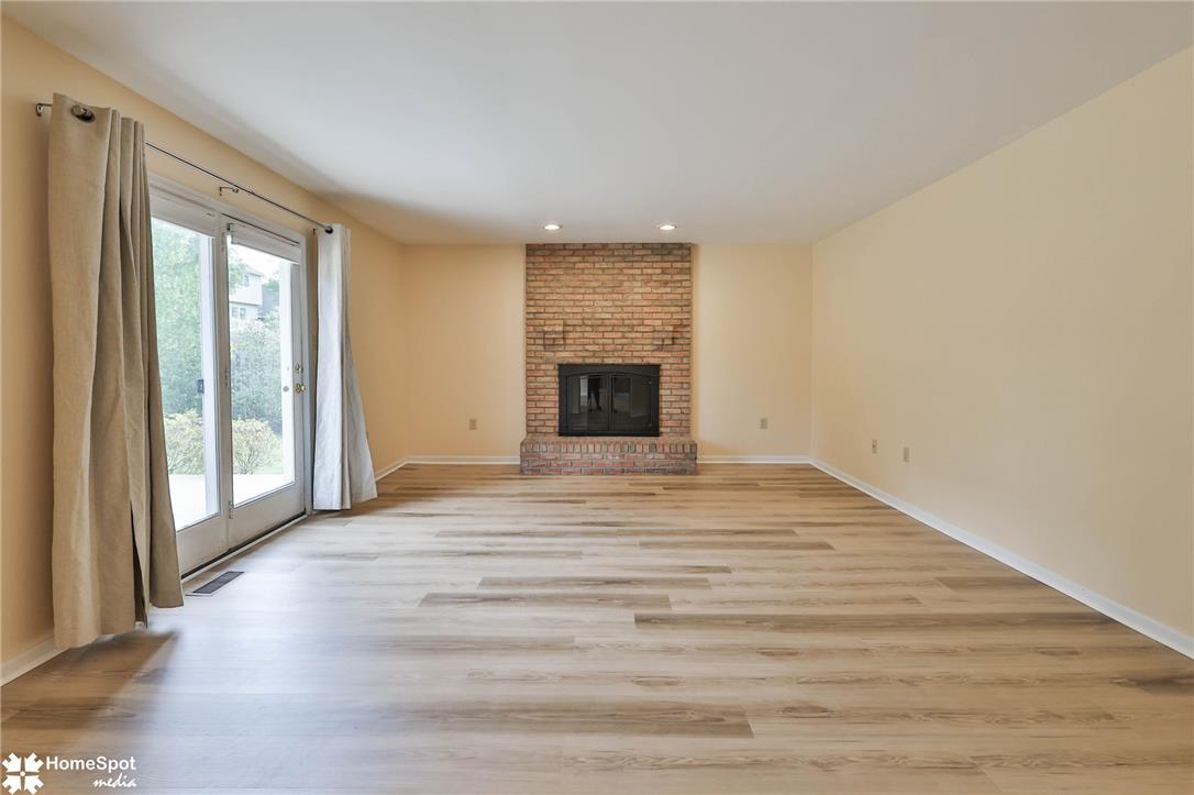 4059 Wedgewood Road Allentown, PA 18104 - Photo 23 of 72 A spacious great room awaits, featuring light wood-style flooring and a charming brick fireplace.