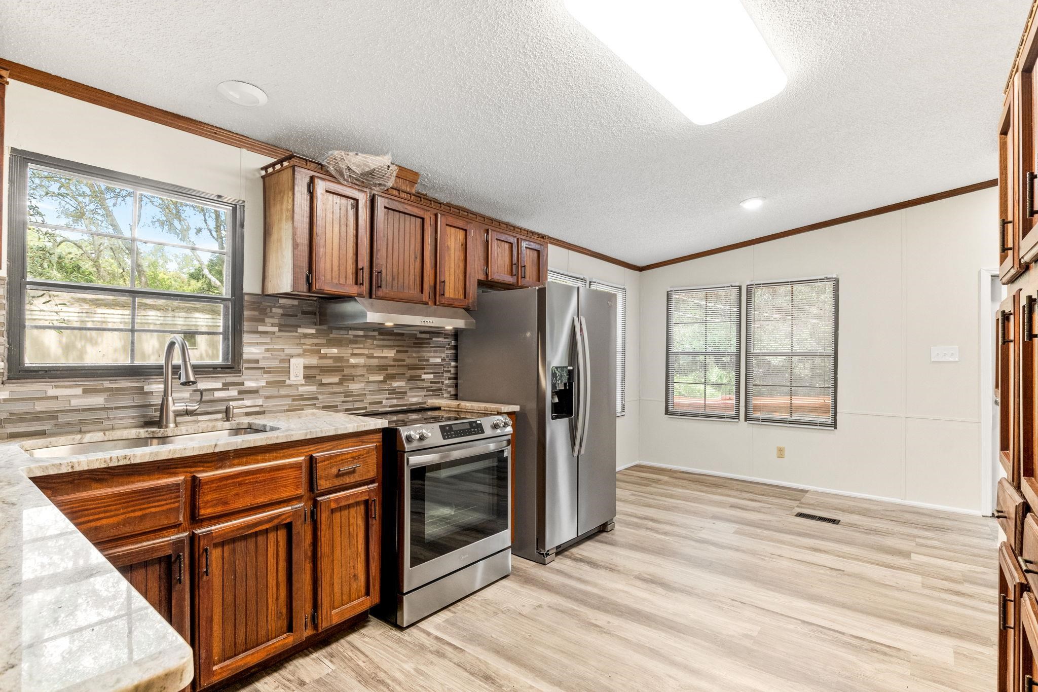 890 Kings Estate Road St. Augustine, FL 32086 - Photo 3 of 38 a kitchen with stainless steel appliances granite countertop a refrigerator a stove a sink dishwasher and wooden cabinets with wooden floor