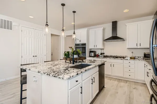 a kitchen with stainless steel appliances granite countertop a sink stove and white cabinets