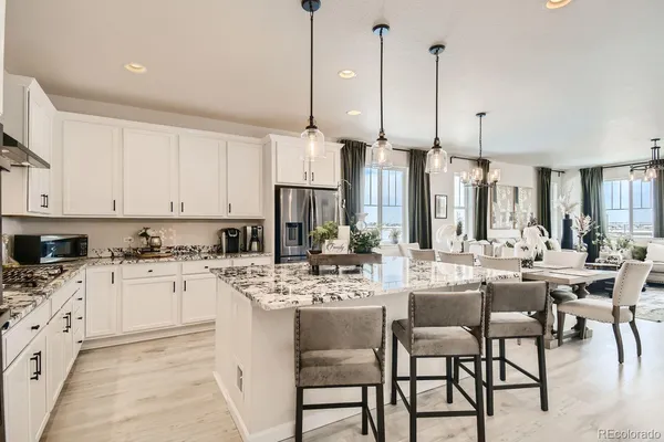 a kitchen with stainless steel appliances kitchen island granite countertop a table chairs and white cabinets