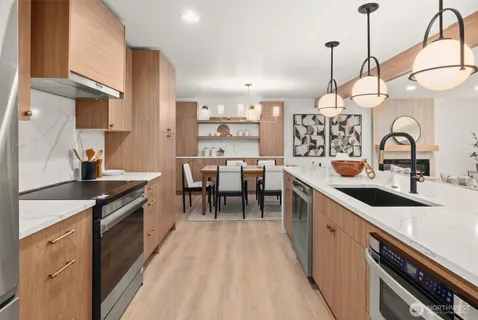 a kitchen with stainless steel appliances granite countertop a sink a stove and a wooden floors