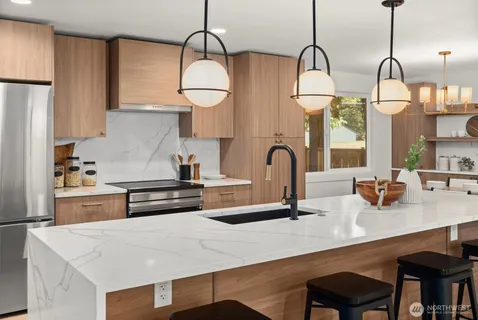 a kitchen with stainless steel appliances a sink a stove and white cabinets with wooden floor