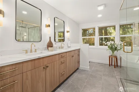 a spacious en suite bathroom with a double vanity sink a large mirror and a bathtub