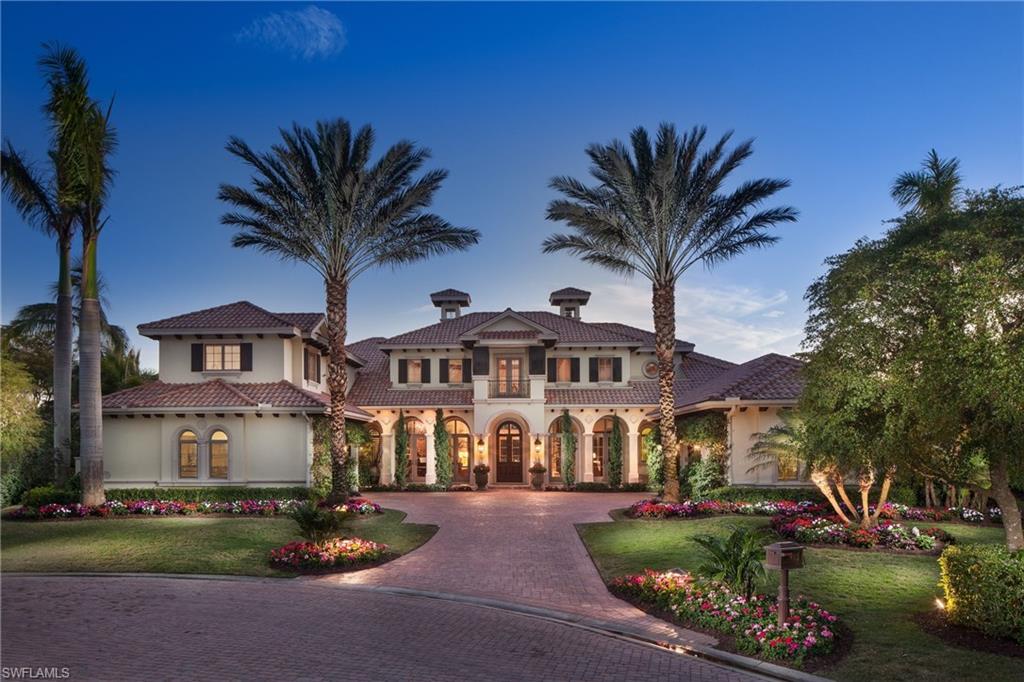 a view of a white house with a yard plants and palm trees