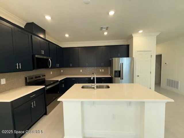 a kitchen with stainless steel appliances a sink a stove a refrigerator a center island and cabinets