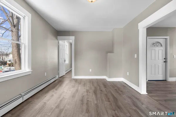 a view of an empty room with wooden floor and a window
