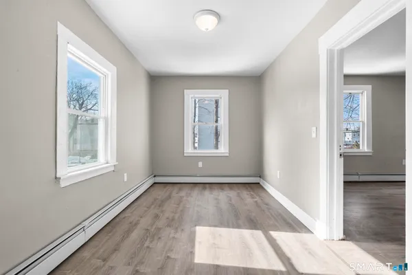 a view of an empty room with wooden floor and a window