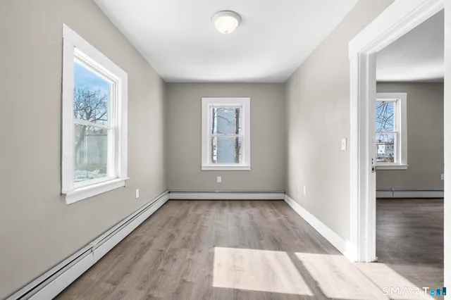 a view of an empty room with wooden floor and a window