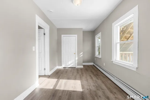 an empty room with wooden floor and windows