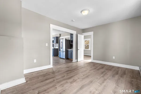 a view of an empty room with wooden floor and windows