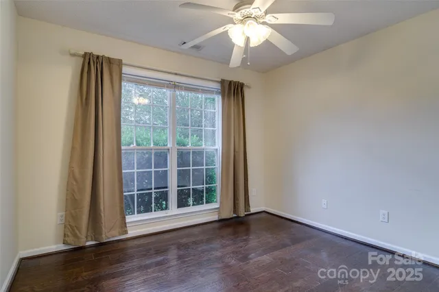 an empty room with wooden floor fan and windows